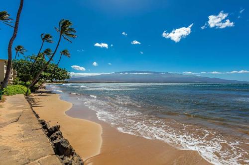 a sandy beach with palm trees and the ocean at Kanai A Nalu 302 in Wailuku