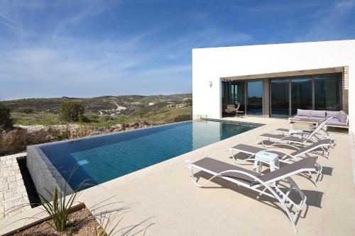 a swimming pool with lounge chairs next to a house at Minthis Resort in Paphos City