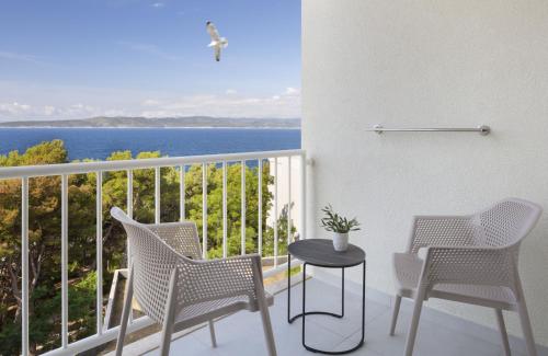 a balcony with chairs and a table and the ocean at Bluesun Hotel Marina in Brela