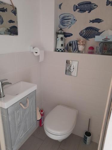 a bathroom with a white toilet and a sink at Chez Tinou in Bacilly