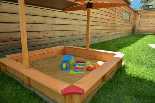 a sandbox with toys in the sand in a backyard at Mountainlodge Luxalpine in San Vigilio Di Marebbe