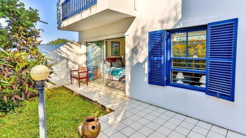 a house with blue shutters on the side of it at Santorini - 8 Pyrgos in Ballito