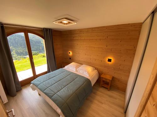 une chambre avec un lit et une grande fenêtre dans l'établissement Charmant appartement: 1 ch, parking, WiFi, animaux admis - FR-1-671-13, aux Gets