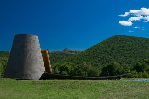 a building in a field with hills in the background at Camping maeva Respire de La Croze in Châtel-Guyon