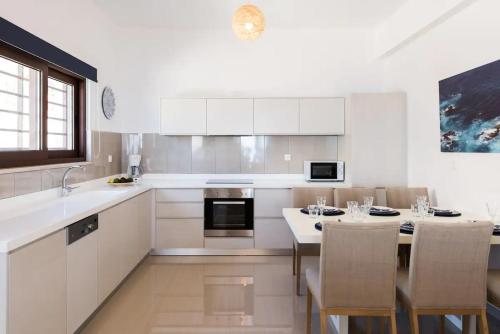 a kitchen with white cabinets and a table with chairs at Villa Alia in Sfakiá