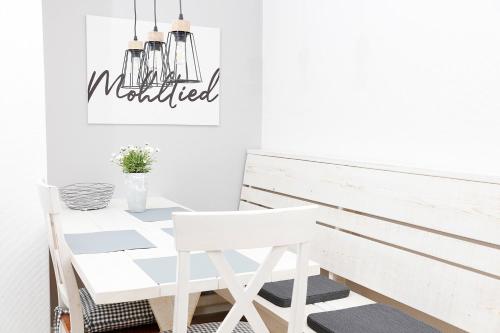 a white dining room with a white table and chair at Landleev - Bauernhof "Hofbude Fehmarn" in Fehmarn