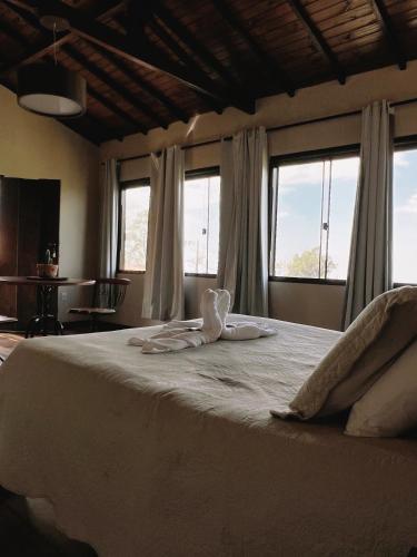 - une chambre avec un grand lit blanc et des fenêtres dans l'établissement Vista da Serra, à Lavras Novas