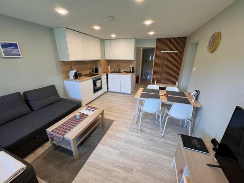 a living room with a couch and tables and a kitchen at Fjord studio in Sunde