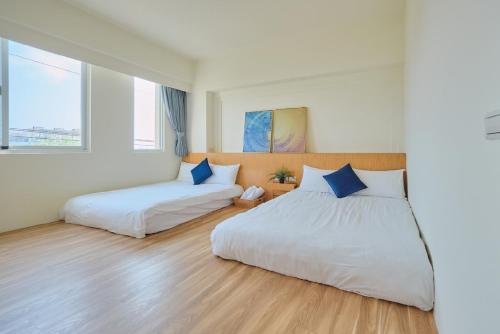 two beds in a room with white walls and wood floors at Golden Sun B&B in Xiaoliuqiu