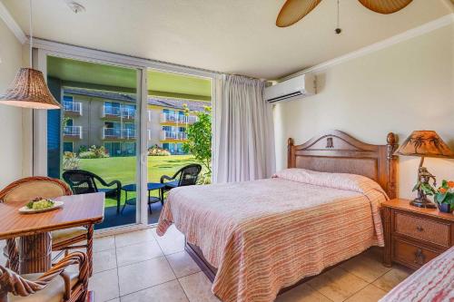a bedroom with a bed and a view of a balcony at Islander on the Beach 115 in Kapaa