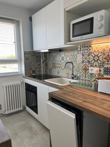 une cuisine avec des armoires blanches, un évier et un micro-ondes dans l'établissement Superbe apart proche transports, à Rueil-Malmaison