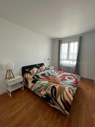 une chambre avec un lit avec une couette colorée et une fenêtre dans l'établissement Superbe apart proche transports, à Rueil-Malmaison
