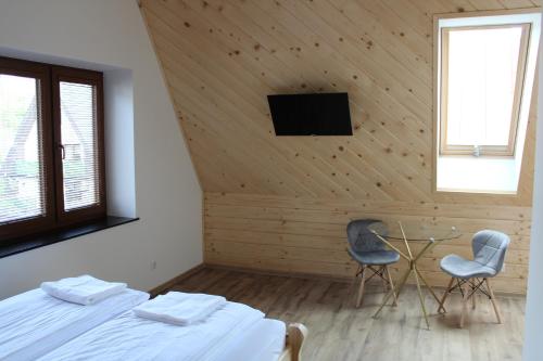 扎科帕内Pokoje Apartamenty Samo Centrum Zakopane ,,Willa Kasztelanka"的一间卧室，有一张床、两把椅子和一台电视