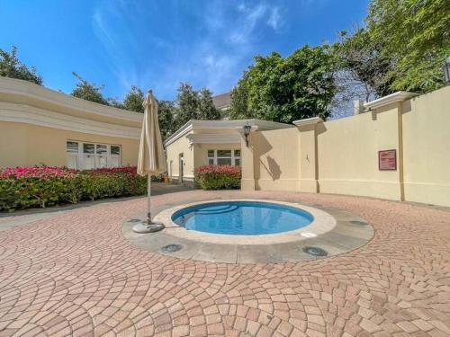 a house with an umbrella and a swimming pool at Peaceful flat in Motor City in Dubai