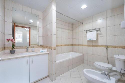 a bathroom with a sink and a tub and a toilet at Peaceful flat in Motor City in Dubai