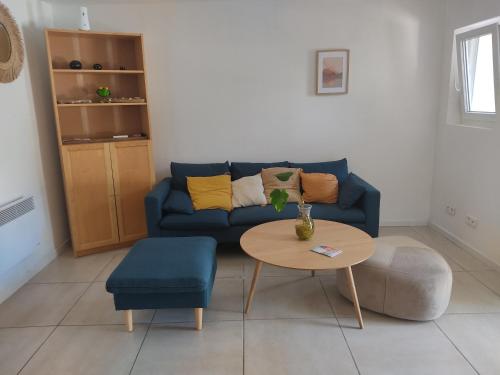 un salon avec un canapé bleu et une table dans l'établissement la ciotat belle maison centre ville avec parking, à La Ciotat