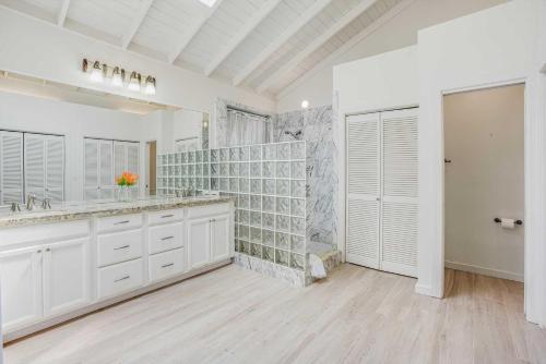 a white bathroom with a sink and a large mirror at Anahola Beach House 6br in Anahola