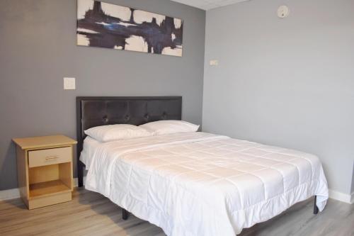 a bedroom with a white bed and a night stand at Elect Inn 5 in Cornwall