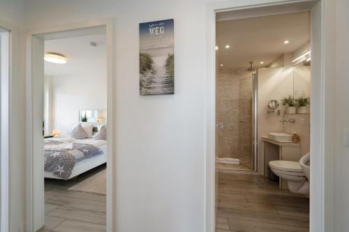 a bedroom with a bed and a bathroom with a toilet at Am Stadtpark in Westerland (Sylt)
