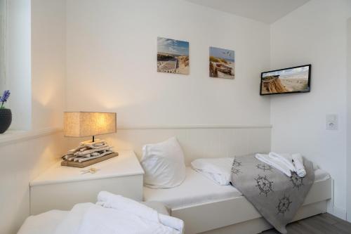 a white room with a table with a lamp and a couch at Am Stadtpark in Westerland (Sylt)