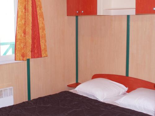 a bedroom with a bed with a red head board at Camping maeva Respire de La Croze in Châtel-Guyon