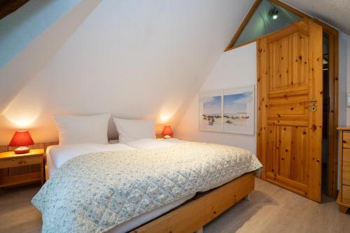 a bedroom with a bed and a wooden door at Sylter Seestern App Ual Skiin in Archsum
