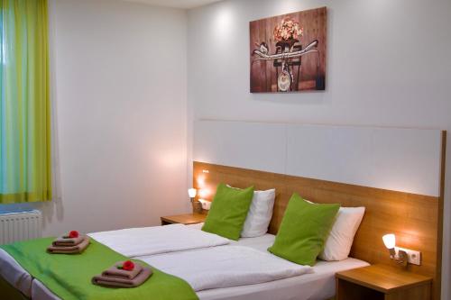 a bedroom with a bed with green and white pillows at B&B Outlet Hotel - Metzingen - Bad Urach - Free Parking in Dettingen an der Erms