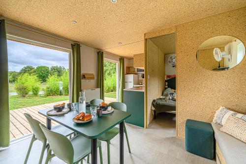 a dining room and living room with a table and chairs at Camping maeva Respire de La Croze in Châtel-Guyon