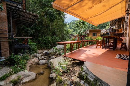 a wooden deck with a river in a yard at ไชยพล โฮมสเตย์ หมู่บ้านแม่กำปอง in Ban Pok Nai