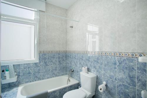 a bathroom with a toilet and a tub and a window at El Rincón de Mónica in Agaete