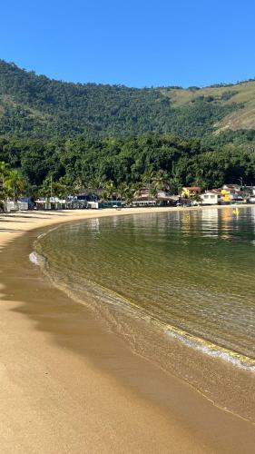 a sandy beach with water and houses in the background at GUEST HOUSE Floresta Mar in Angra dos Reis
