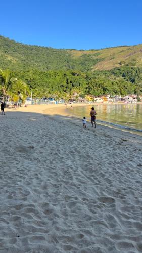 a woman and a child walking on a beach at GUEST HOUSE Floresta Mar in Angra dos Reis