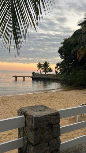 a white fence on a beach with a pier at GUEST HOUSE Floresta Mar in Angra dos Reis