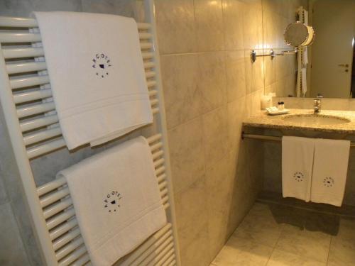 a bathroom with a sink and a shower with towels at Arcotel in Villanova Monferrato