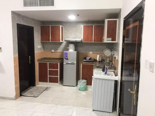 a kitchen with wooden cabinets and a refrigerator at Apartment in Ajman,furnished studio in Ajman 