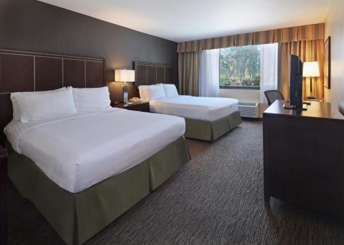 a hotel room with two beds and a television at Holiday Inn Hotel & Suites Anaheim by IHG in Anaheim