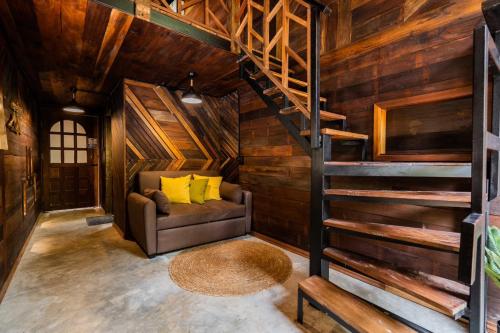 a living room with a couch and stairs in a cabin at ไชยพล โฮมสเตย์ หมู่บ้านแม่กำปอง in Ban Pok Nai