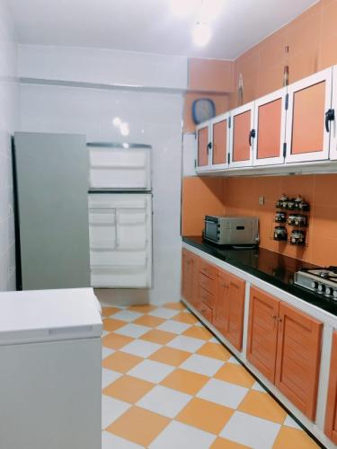 une cuisine avec des armoires orange et blanches et un réfrigérateur dans l'établissement اقامة علي, à Al Hoceïma