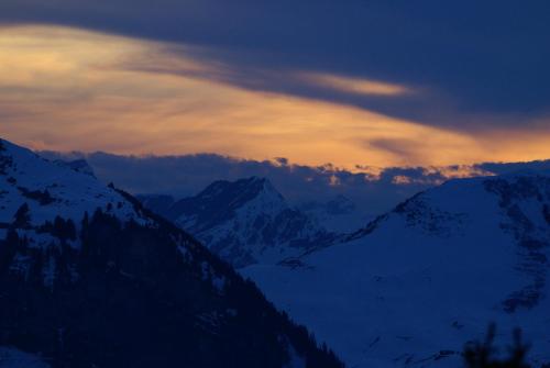 a sunset over a snow covered mountain range at Posthotel Rössli in Gstaad