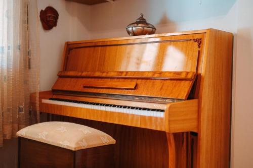 a wooden piano in a room with a stool at Sylvi Maisonette Volos in Melissátika