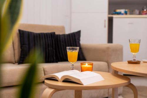 a coffee table with two glasses of orange juice and a book at Eden - A Night near Athens Int Arpt in Spáta