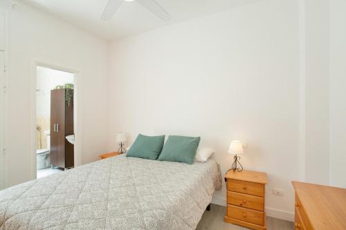 a white bedroom with a bed and a wooden dresser at El Rincón de Mónica in Agaete