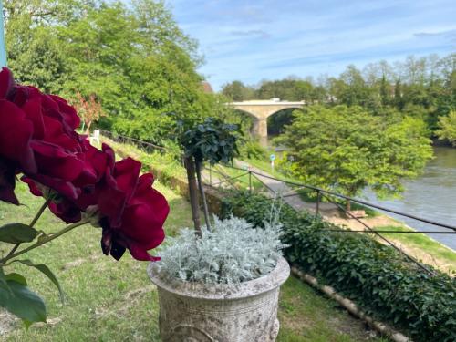 a flower pot with red roses and a bridge at La Rebière d'Or, B&B et Gîte in Mouleydier
