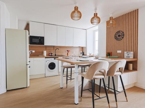 une cuisine avec des armoires blanches et une table et des chaises dans l'établissement le macareux, à Perros-Guirec