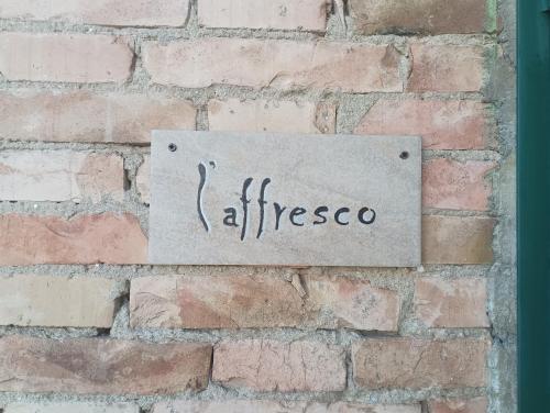 a sign on the side of a brick wall at L'Affresco in Cetona