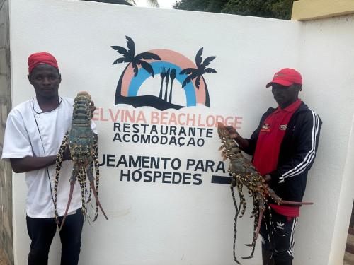 two men standing in front of a sign holding uparantulas at Telvina Beach Lodge in Vilanculos