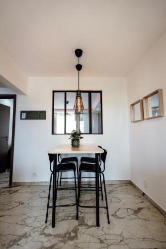 a dining room table with two chairs and a chandelier at Prestige Lumineux Jacuzzi Parking privé in Mulhouse