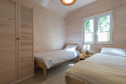 a bedroom with two beds and a window at Off White Domki Darłówko in Darlowko