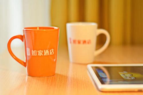 two coffee cups sitting on a table next to a tablet at Home Inn Shanghai Nicheng Lingang Facility Industrial Park in Nanhui