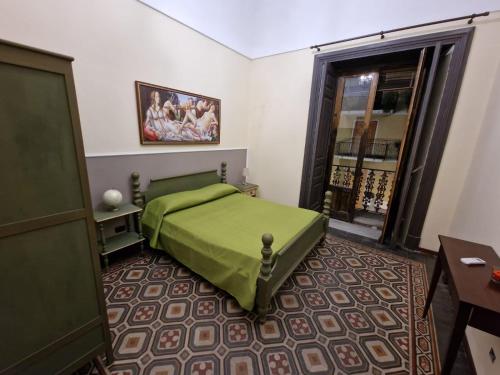a bedroom with a green bed and a window at L'Alloggio dell'Artista in Belpasso